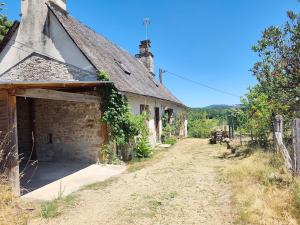 an old stone house with a garage in a field at La Salagnac in Corrèze