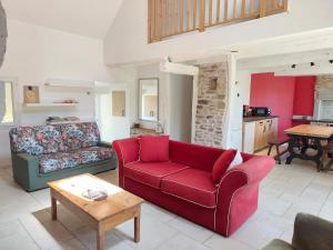 a living room with a red couch and a table at La Salagnac in Corrèze
