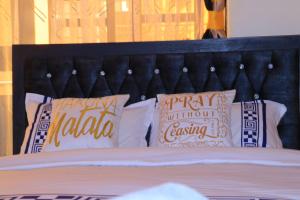 a bed with a black headboard and pillows with the words happy nola at Cedar Suites in Juja
