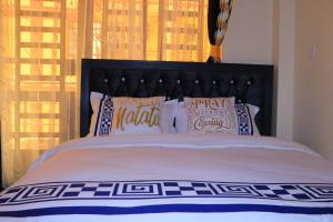 a bed with a black headboard and pillows on it at Cedar Suites in Juja