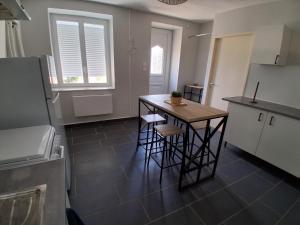 a kitchen with a small table and stools in it at Agréable Maison in Le Magny