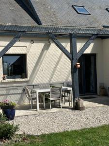 a patio with a table and chairs in front of a house at Au fil des champs in Soyécourt