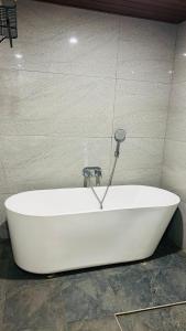 a white bath tub with a faucet on a wall at Savana Luxury Stay in Pondicherry +34 photos
