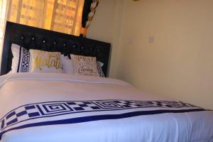 a bedroom with a large bed with a black headboard at Cedar Suites in Juja