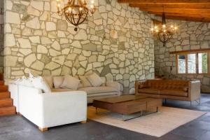 a living room with a couch and a stone wall at Finca en el Bosque Huasca de Ocampo con Alberca in Huasca de Ocampo
