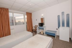 a room with two beds and a desk and a window at Rhodopi Hotel Plovdiv in Plovdiv