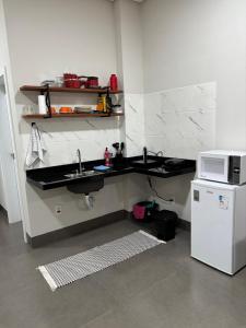 a kitchen with a sink and a microwave at Apartamento casa da Lu 102 in Primavera do Leste