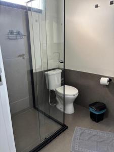a bathroom with a toilet and a glass shower at Apartamento casa da Lu 102 in Primavera do Leste