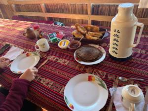 a person sitting at a table with plates of food at Casa de Ruben - Lac Titicaca in Llachon