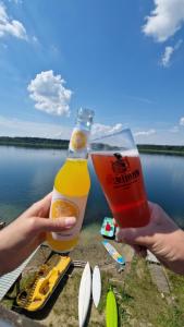 Eine Person hält ein Glas Bier vor einem See in der Unterkunft Na Molo in Głębokie
