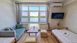 ein Wohnzimmer mit einem Bett, einer Couch und einem Fenster in der Unterkunft Na Molo in Głębokie