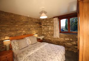 a bedroom with a bed and a stone wall at David's Organic Farm Wales in Llanfallteg