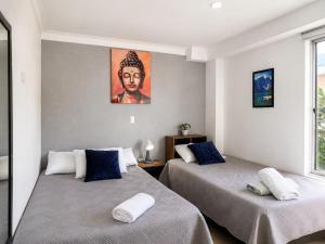 two beds in a room with a painting on the wall at Coliving Compostela in Medellín
