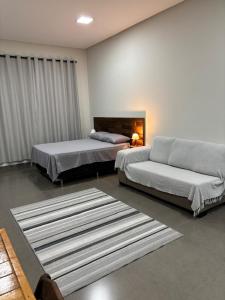 a bedroom with two beds and a couch and a rug at Apartamentos casa da Lu 101 in Primavera do Leste