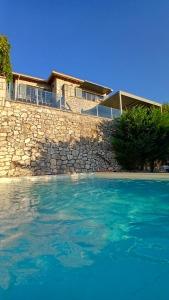 a house with a stone wall and a swimming pool at Villa Lydia in Meganisi
