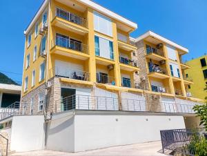 a yellow building with balconies on top of it at LouAdria Apartments in Đenovići