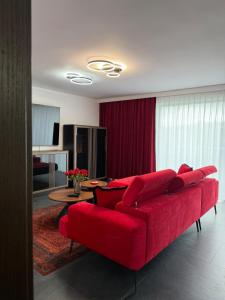 a living room with a red couch and a table at Sadowa Ostoja z prywatnymi jacuzzi in Pierwoszyno