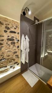 a bathroom with a shower and a stone wall at Nervia Rooms by Talking Stones in Dolceacqua +10 photos