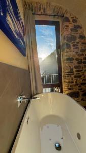a bathroom with a bath tub with a window at Nervia Rooms by Talking Stones in Dolceacqua