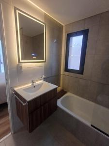 a bathroom with a sink and a tub and a mirror at Bonhomía Torre Quartz in Neuquén +13 photos