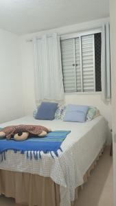 a bedroom with a bed with blue pillows and a window at Small family apartment in Sao Sebastiao
