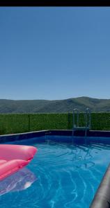 a swimming pool with blue water and a red pillow at Modern Mountain Villa with Pool near Tbilisi in Bulach'auri