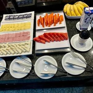 a table with plates and utensils and fruits and vegetables at Hotel Premier in Belo Horizonte