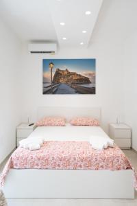 a white bedroom with a bed and a painting on the wall at Aragonese Apartments in Casa Chiaiozza