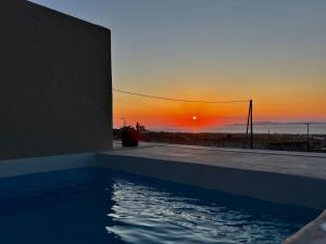 a swimming pool with a sunset in the background at Bevimar Suites with Private Pool and Non Heated Jacuzzi in Santorini