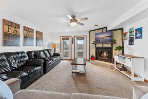 a living room with a black leather couch and a fireplace at Dells Family Stacation in Wisconsin Dells