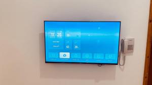 a flat screen tv hanging on a wall with a phone at شقق أماسي الواحة بالعقيق in Al ‘Aqīq