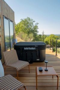 a deck with a grill and two chairs and a table at L'Instant Des Amants in Sorèze