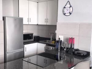 a kitchen with white cabinets and a stainless steel refrigerator at DURBAN BEACHFRONT Tenbury 903 in Durban