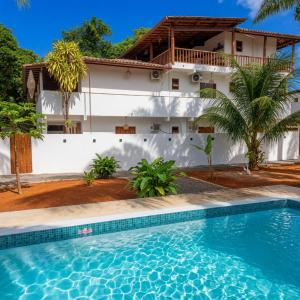 a villa with a swimming pool in front of a house at Residência Thomas in Itacaré