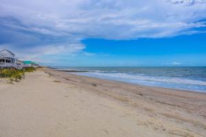 a sandy beach with a house and the ocean at Hazel Q in Edisto Island