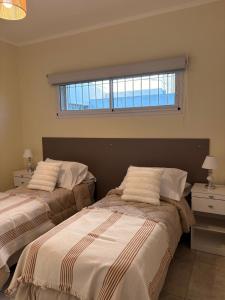 two beds in a bedroom with a window at Punto San Martin in Venado Tuerto