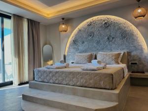 a bedroom with a large bed with a stone headboard at Bevimar Suites with Private Pool and Non Heated Jacuzzi in Santorini