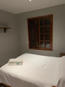 a bedroom with a white bed with two towels on it at Casa Calma in Eldorado