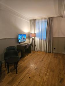 a living room with a desk and a television at Orange Parkway Hotel in Diest