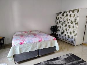 a bedroom with a bed with a floral bedspread at Microcasa espaçosa e acolhedora in Caraguatatuba