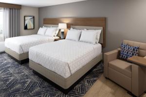 a hotel room with two beds and a chair at Candlewood Suites Rowlett - Lake Ray Hubbard by IHG in Rowlett +29 photos