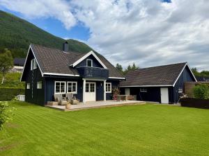 a black house with a large yard with green grass at Scenic Private House Surrounded by Nature in Sæbø
