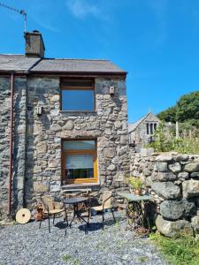 a stone cottage with a table and chairs in front of it at Brynhyfryd in Llanaelhaiarn