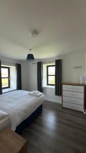 a bedroom with a large bed and two windows at Dwellinghouse, Inishmore in Ourtnagapple