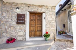 a stone house with a wooden door and flowers at Annalì in Trentinara