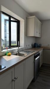 a kitchen with white cabinets and a sink and a window at Dwellinghouse, Inishmore in Ourtnagapple