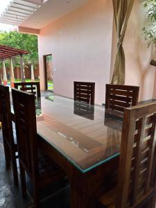 a dining room table with chairs and a wooden table with a glass top at Villa Saffron Luxury Pvt Pool in Pondicherry