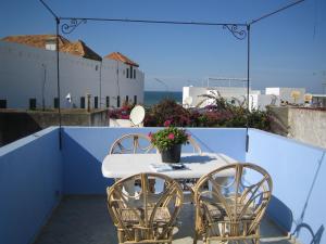Una mesa y sillas en un balcón con vista al mar. en Dar Candal, en Asilah