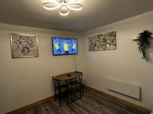 a room with a table and a tv on a wall at Stardust Getaway Tiny-Home E32AK40 in Piltown