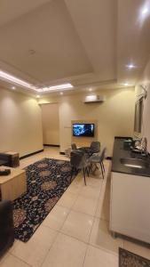 a living room with a table and chairs and a tv at sala almasa serviced apartments in Abha